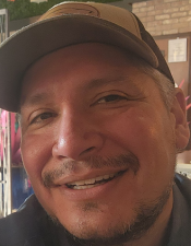 Aaron Castillo, the owner of Auto TL, smiling and wearing a baseball cap.