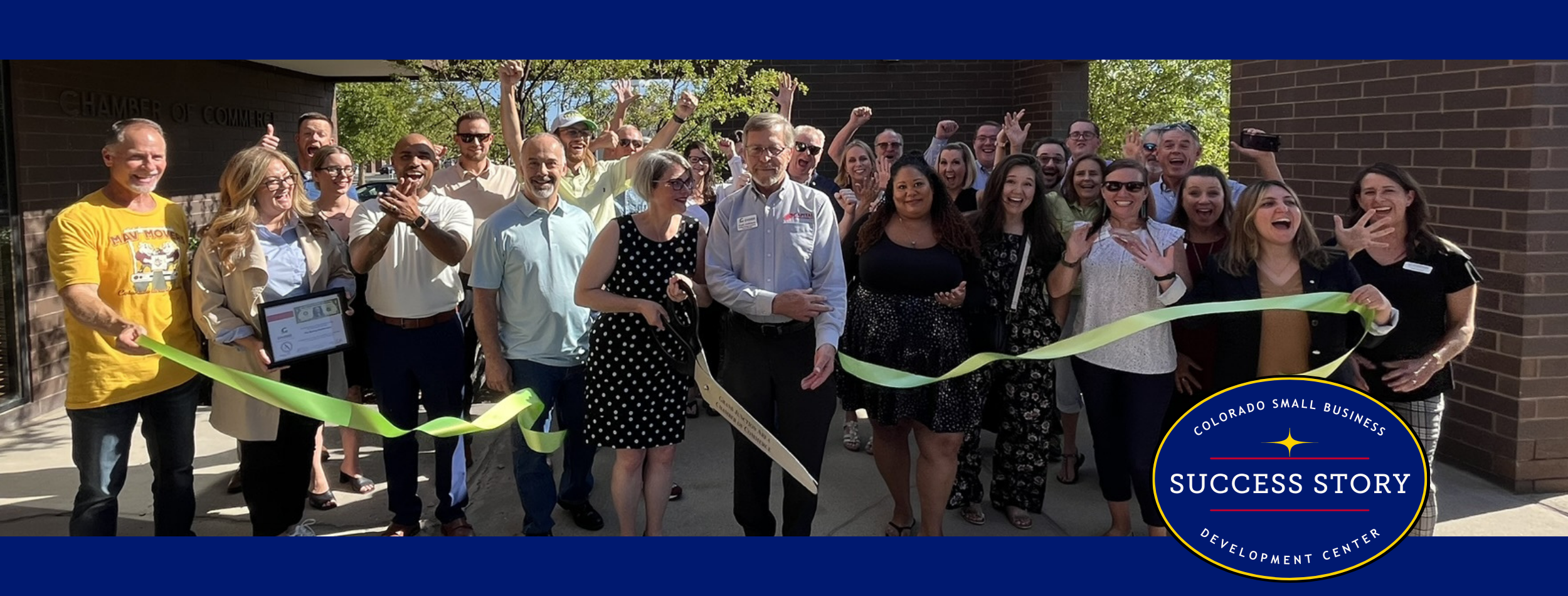 a group of people cutting a ribbon in front of a building.