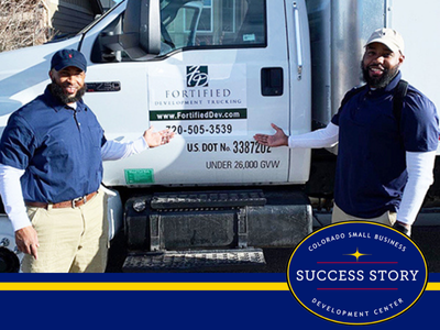 two people standing in front of a white truck.