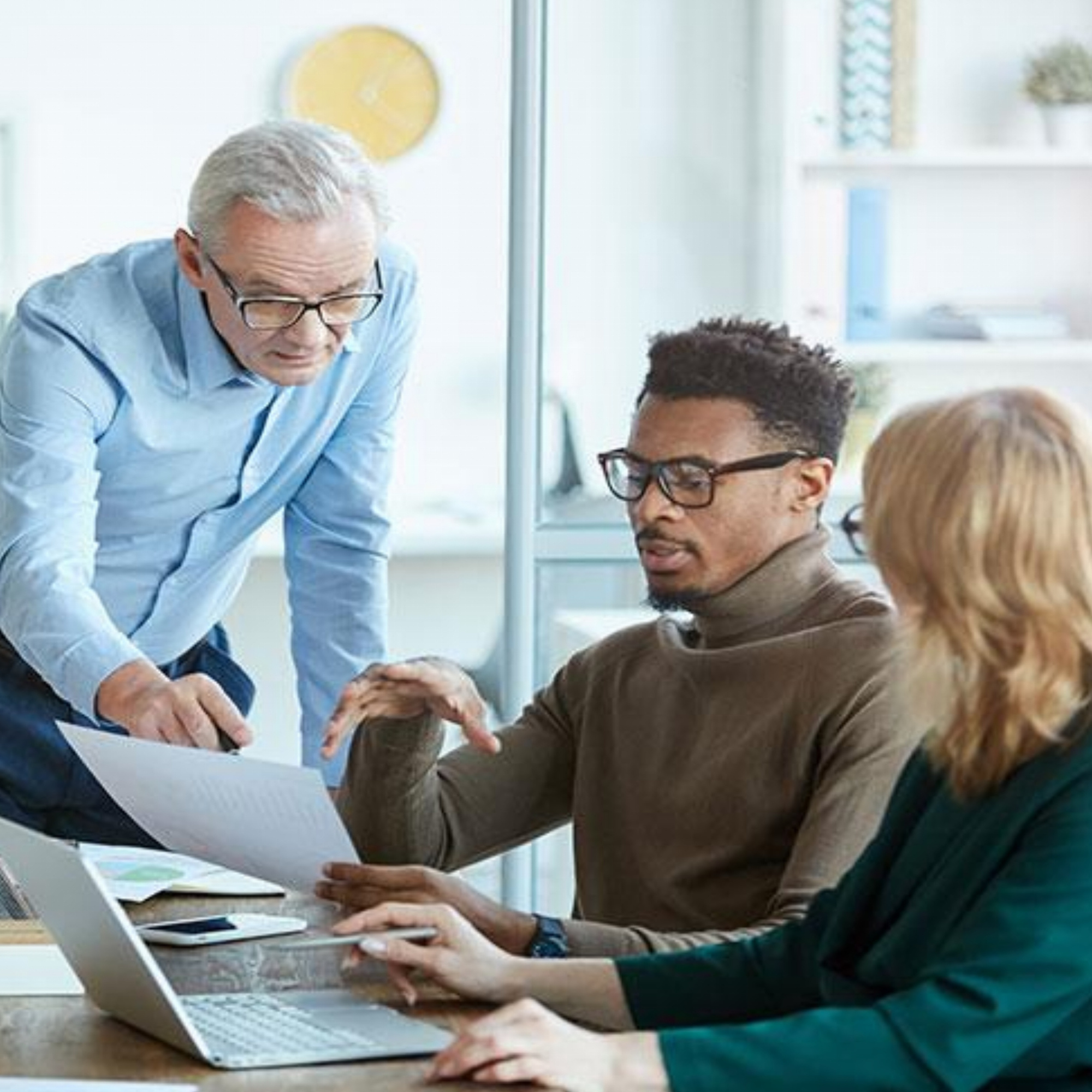a group of people looking at a document on a laptop.