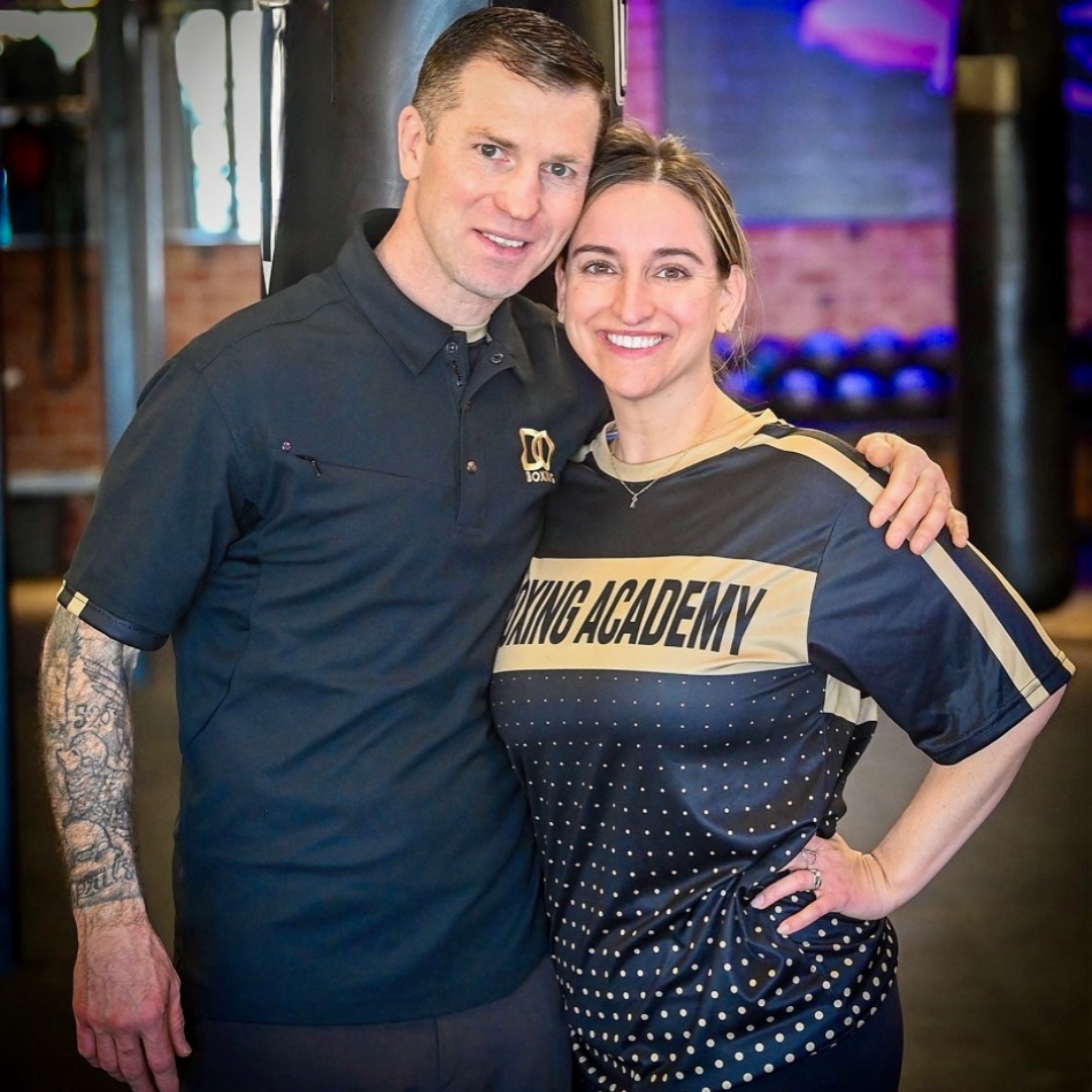 a couple posing for a photo in a gym.