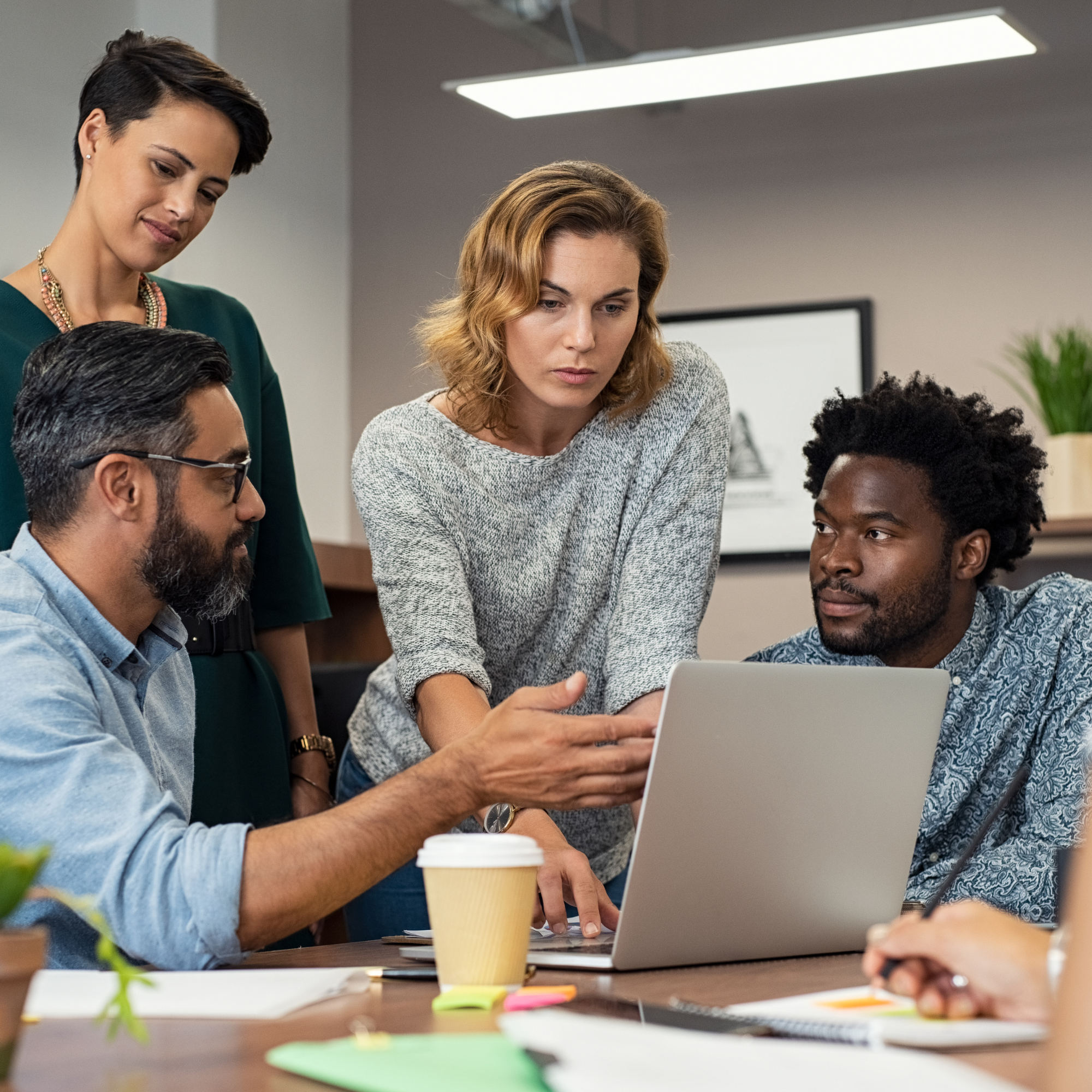 a group of people working on a laptop in an office.
