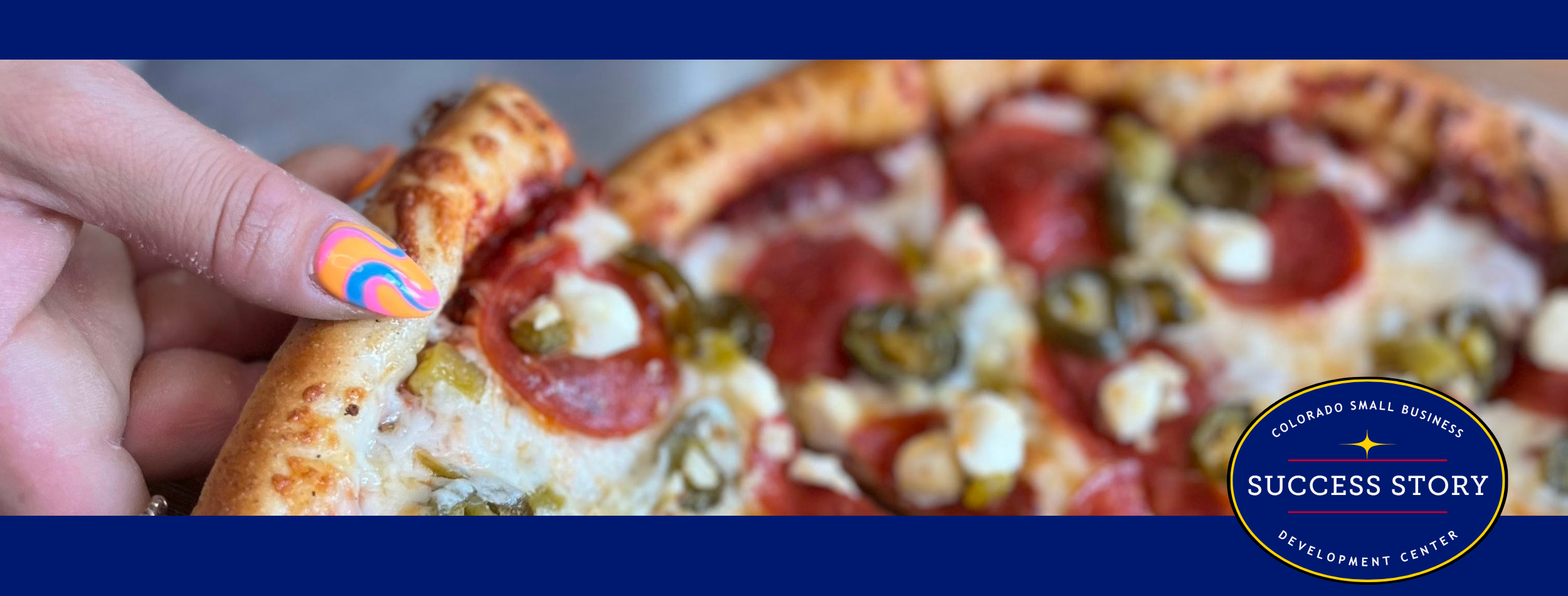 a hand holding a slice of pepperoni pizza next to a glass of beer.