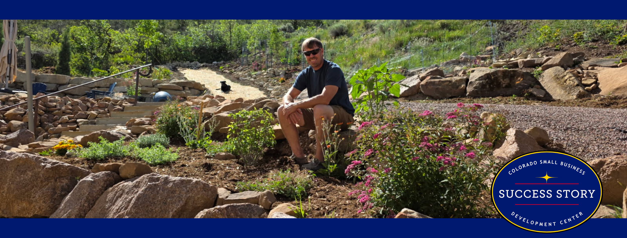 A person sitting on top of some rocks in a garden in the mountains.