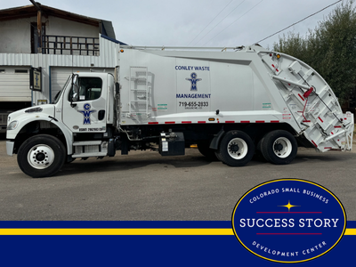 a garbage truck parked in front of a building.