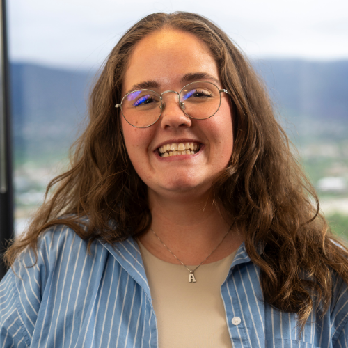 a person with glasses and a blue shirt smiling.
