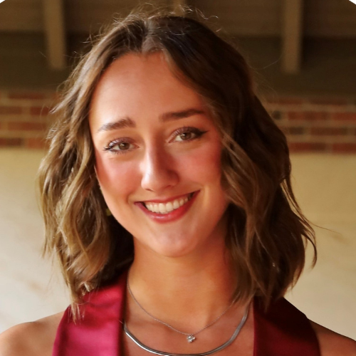 a woman in a maroon dress smiling at the camera.