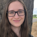 Woman with long brown hair and glasses smiling