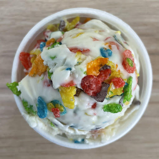 A close up of ice cream in a bowl topped with fruity pebbles bits.