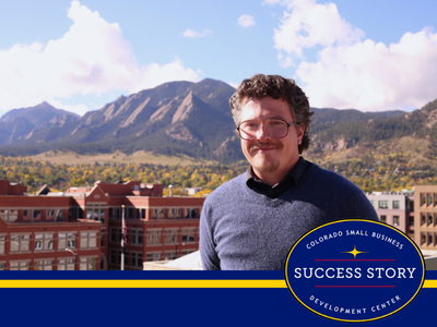 The image shows a portrait of a man in glasses in front of the Boulder Flatiron mountain landscape with some buildings in the background.