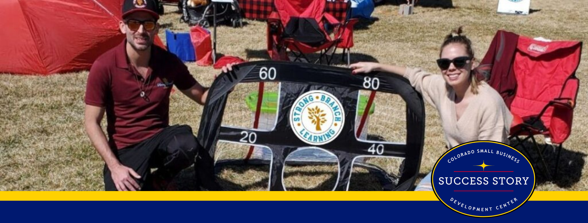 two people pose with a kite on a grassy field.