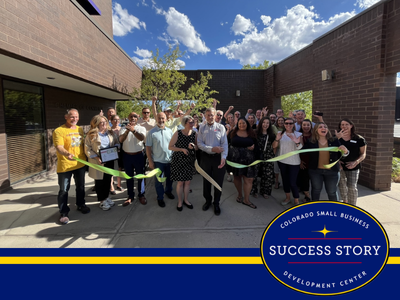 a group of people cutting a ribbon in front of a building.