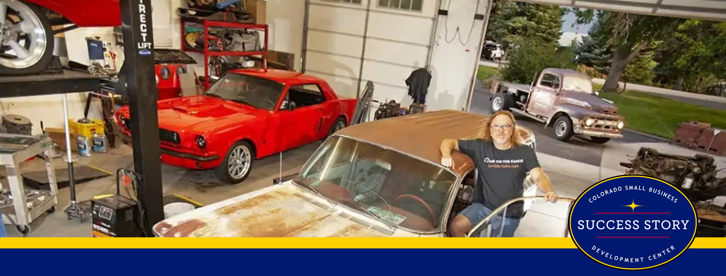 a person standing next to an old car in a garage.