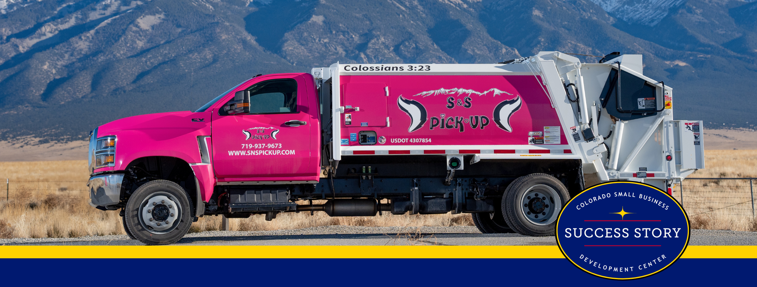 a pink garbage truck with mountains in the background.