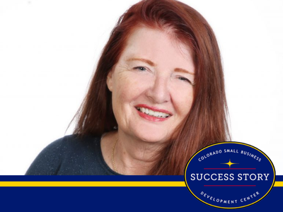 A smiling person with long auburn hair facing forward.