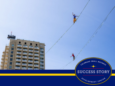 two people on a tightrope in front of tall buildings