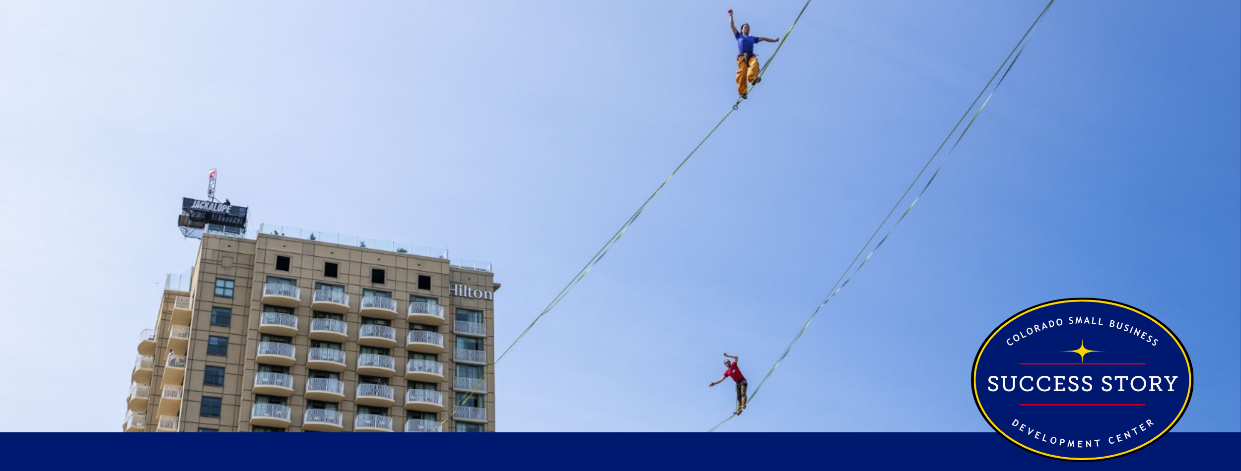 two people on a tightrope in front of a tall building