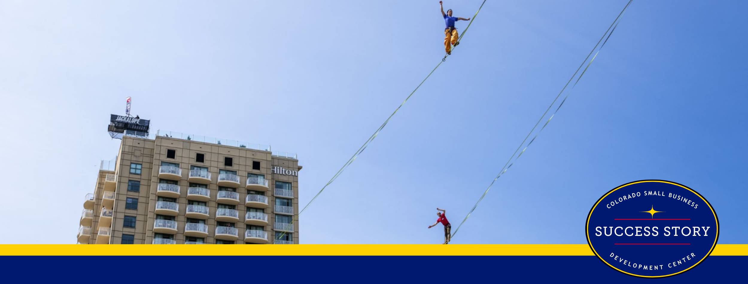 two people on a tightrope in front of tall buildings