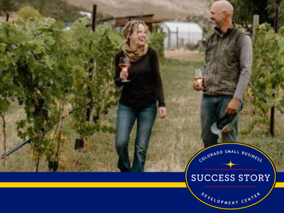 Two people walking through a vineyard.