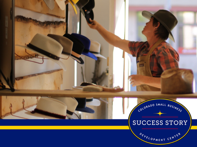 A person wearing an apron arranging cowboy hats on a wall.