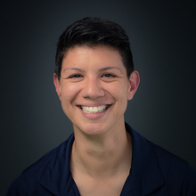 a person in a blue shirt smiling at the camera.