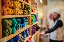 Shelves of colorful yarn with a woman in the background
