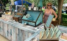 Local female artist standing in front of jewelry booth at a summer market